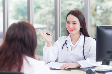 Asian professional woman doctor give suggestion of healthcare information to her patient in examination room at hospital.