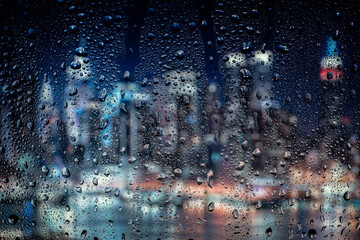 Night city lights through window with rainwater and drops. Background with bokeh.