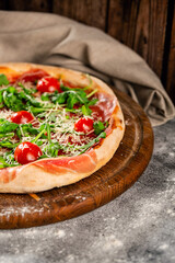 Traditional New York style pizza with prosciutto arugula and cherry tomatoes.