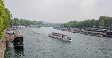 View of Passerelle Debilly (Debilly Footbridge) . A ship sails along the Seine. In the ports there are ships