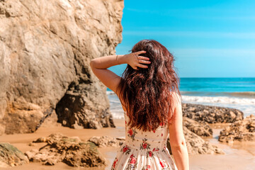 Beautiful woman in dress on Matador Beach near Los Angeles, beautiful rocks and ocean
