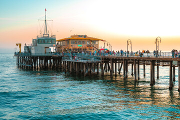 Fototapeta premium Santa Monica Pier on the background of an orange sunset, calm ocean waves, Los Angeles, California