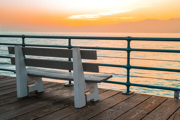 Fototapeta na wymiar Beautiful sunset on the ocean in California, an empty bench on a wooden pier