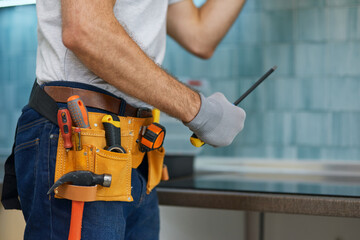 Expert. Cropped shot of young repairman, professional plumber holding a screwdriver while fixing a...