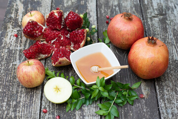 Creative layout of traditional symbols for jewish holiday- apples, honey, pomegranate on wooden background. Concept Rosh Hashanah tova jewish New Year. Top view, copy space, fresh fruits