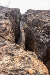 Large crack in the rock consisting of small round stones. Vertical image.