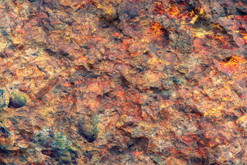 Background texture of natural wall made of brown, red, and yellow stones. Horizontal image.