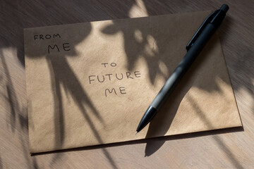 Craft envelope and pencil in the rays of sun and the shadows of plants. A letter to the future, is written on the envelope: from me to future me