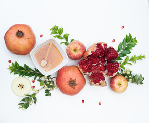Beautiful layout of traditional symbols for jewish holiday - apples, cup with honey, pomegranate, green branch on white background. Concept Rosh Hashanah tova jewish New Year. Top view, fresh fruits