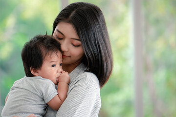 Young beautiful asian mother lifting and playing with her baby.