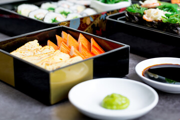 Set of variety sushi, Tamagoyaki, crabsticks sushi and maki in bento box served with soy sauce and wasabi. Delicious japanese food.