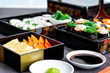 Set of variety sushi, Tamagoyaki, crabsticks sushi and maki in bento box served with soy sauce and wasabi. Delicious japanese food.