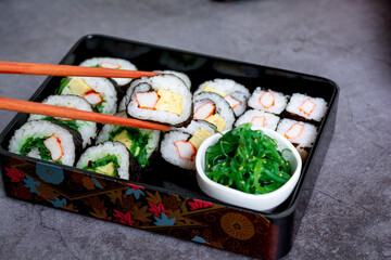 Eatting tamagoyaki maki with wooden chopsticks and soy sauce in white bowl. Delicious japanese food.