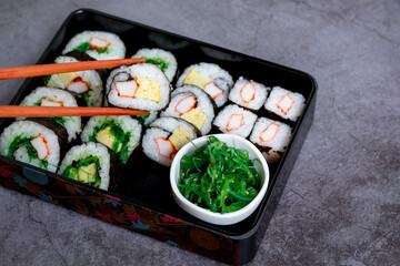 Eatting tamagoyaki maki with wooden chopsticks and soy sauce in white bowl. Delicious japanese food.