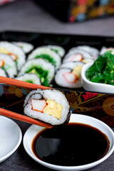 Eatting tamagoyaki maki with wooden chopsticks and soy sauce in white bowl. Delicious japanese food.