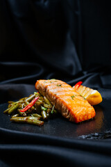 grilled salmon with vegetables on a black background