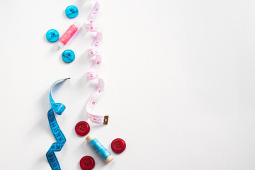 Sewing materials - a box with threads of bright colors, a pink ribbon, as well as a notebook for text on a white background. Frame, space for text