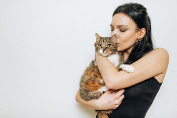 Young beautiful brunette kissing a cat in her arms