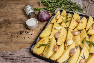 Spiced pieces of raw potato prepared to bake on old table