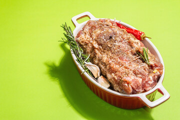 Raw pork roll stuffed with garlic and carrots in a ceramic roasting dish