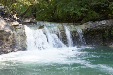 Fototapeta na wymiar Rapid water flow and waterfall in the bed of the Zhane River in the North Caucasus