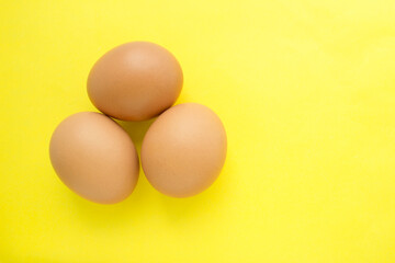 Three chicken eggs on a yellow background