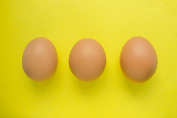 Three chicken eggs on a yellow background