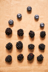 Five blueberries and twelve blackberries on a beige background, laid out in the form of a house. High quality photo