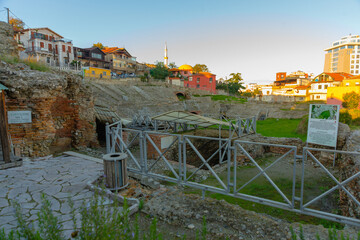 DURRES, ALBANIA: Exterior of ancient Roman amphitheater with surrounding buildings in the city of...