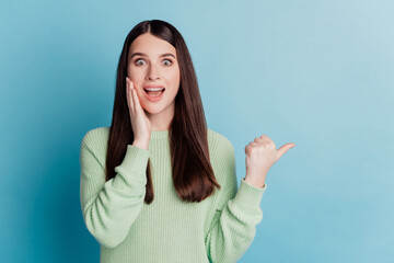 Portrait of a crazy shocked girl pointing thumb away empty space open mouth sale reaction