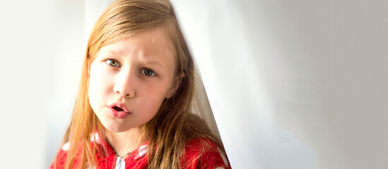 Portrait of a disgruntled, offended young girl with blonde hair looks angrily and does not agree with someone's opinion wears red clothes, on a white background with space for text and selective focus