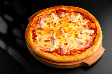 Pizza is not a wooden board. Black background. close-up.
