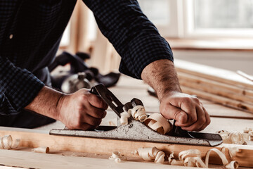 Carpenter's hands planing a plank of wood with a hand plane - obrazy, fototapety, plakaty
