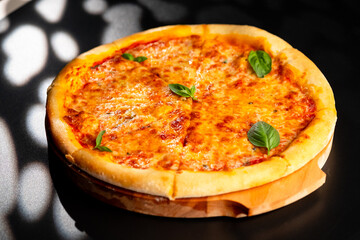 Pizza is not a wooden board. Black background. close-up.