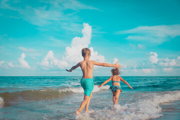 little girl and boy run and play with water at beach