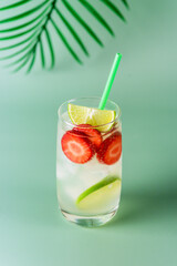 Glass of Tasty and Cold Strawberry and Lime Lemonade Summer Cold Drink Green Background Vertical
