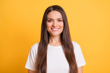 Photo portrait of brunette woman smiling wearing white t-shirt isolated on bright yellow color...