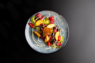Grilled smoked sausages and baked potatoes on a gray plate, decorated with cherry tomatoes and Chinese cabbage leaves with white sauce.