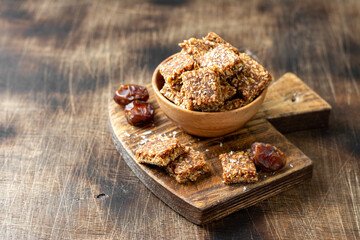 Coconut cookies with dates and carrots in a wooden bowl on a brown background closeup. The concept of a healthy snack no sugar