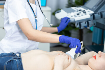 A young doctor examines a patient's breast with an ultrasound. Preventing the onset of breast cancer. Doctor's office.