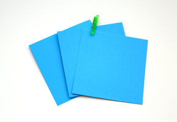 Turquoise, blue colored note papers shot on White while green clothespin hold them.