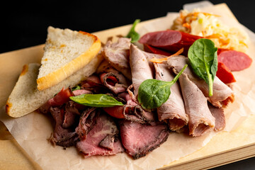 Various meat delicacies in the range. A meat plate. Serving on a wooden cutting dos on a black background.