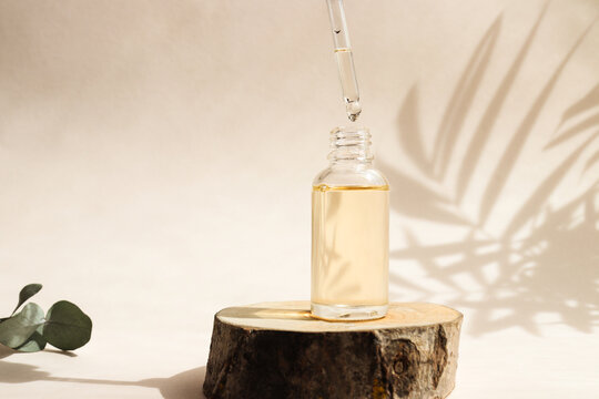 Bottle of cosmetic essential oil with dropper on a wood cut close-up. Hard light. Beauty concept. Serum skin care product
