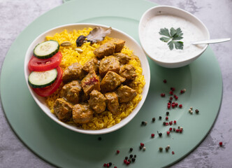 Garnished chicken Madras with Pulao rice in a white bowl