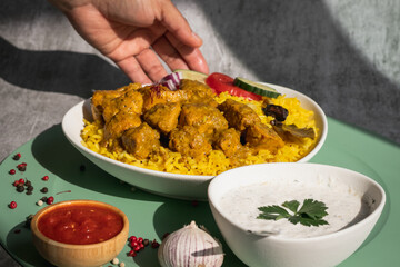 Garnished chicken Madras with Pulao rice in a white bowl