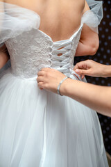 Obraz na płótnie Canvas The girl fastens the white dress of the bride 