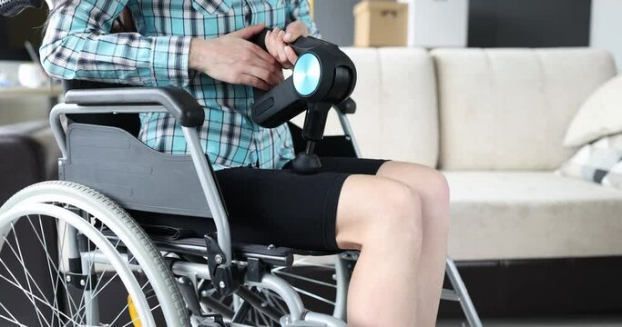 Woman in a wheelchair massaging her leg with percussion massager 4k movie