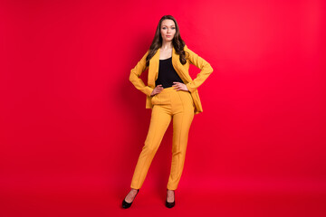Full length body size view of attractive classy girl leader posing hands on hips isolated over bright red color background