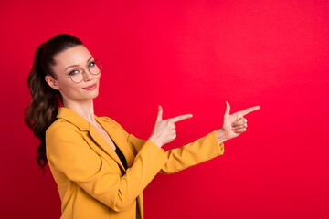 Photo of sweet pretty woman wear yellow jacket spectacles smiling pointing fingers empty space isolated red color background