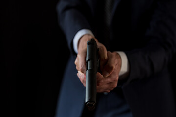 古いセミオートマチックピストルを構えるスーツの男性